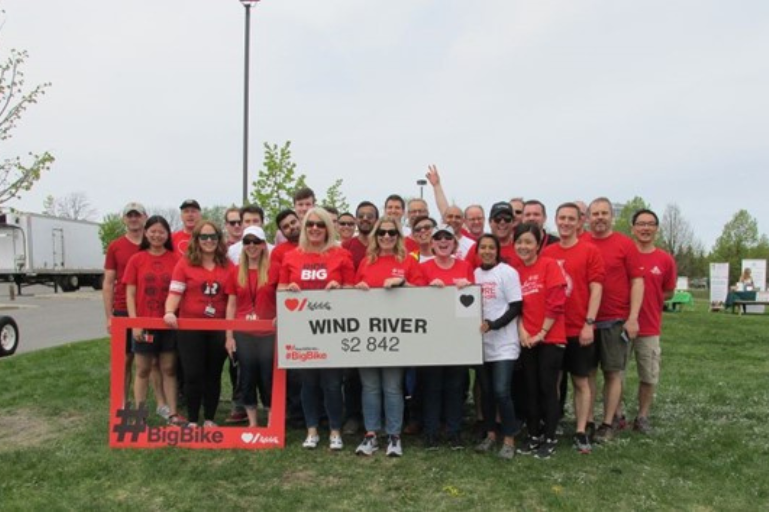 The Wind River team poses for a team photo with a cheque for charity at an outdoors event.