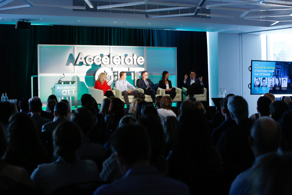 Panel of industry leaders speaking at an AccelerateOTT event, with an audience gathered to discuss innovation and business growth in Ottawa.