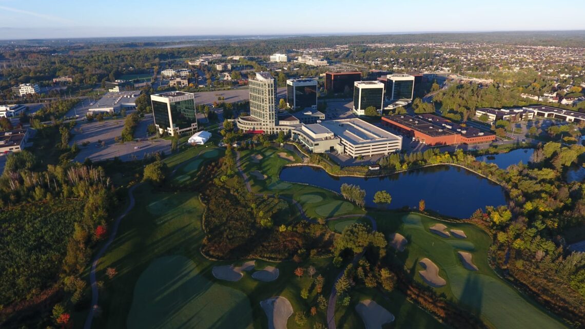 Aerial view of Kanata North’s tech park, featuring modern office buildings surrounded by green space, a golf course, and a pond.