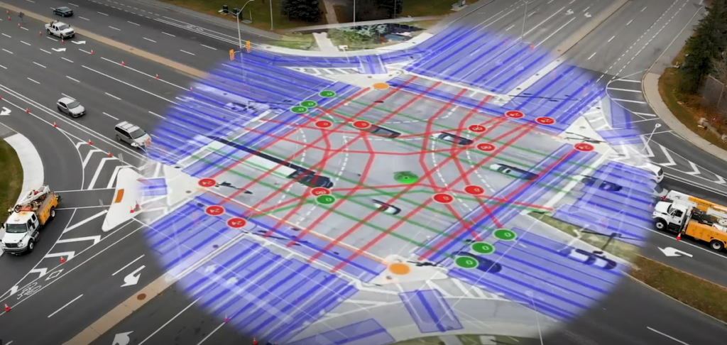 Aerial view of an intersection with overlaid sensor and data visualization, representing connected vehicle technology and smart traffic systems.