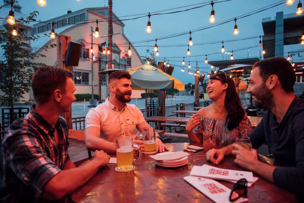 Friends enjoying drinks and conversation on an outdoor patio under string lights in the evening, reflecting Ottawa’s vibrant social life.