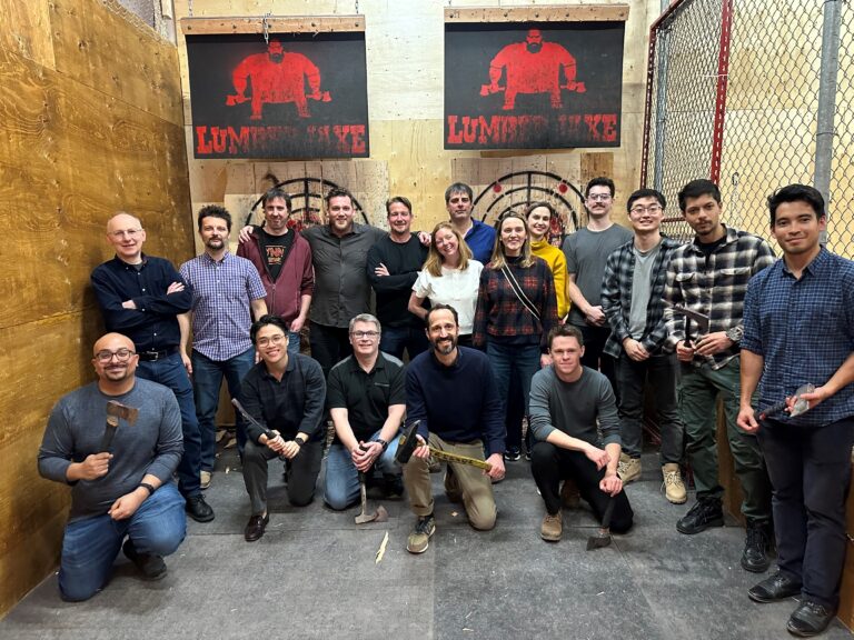 Team of professionals participating in a group activity at an axe-throwing venue, representing workplace culture and team building.