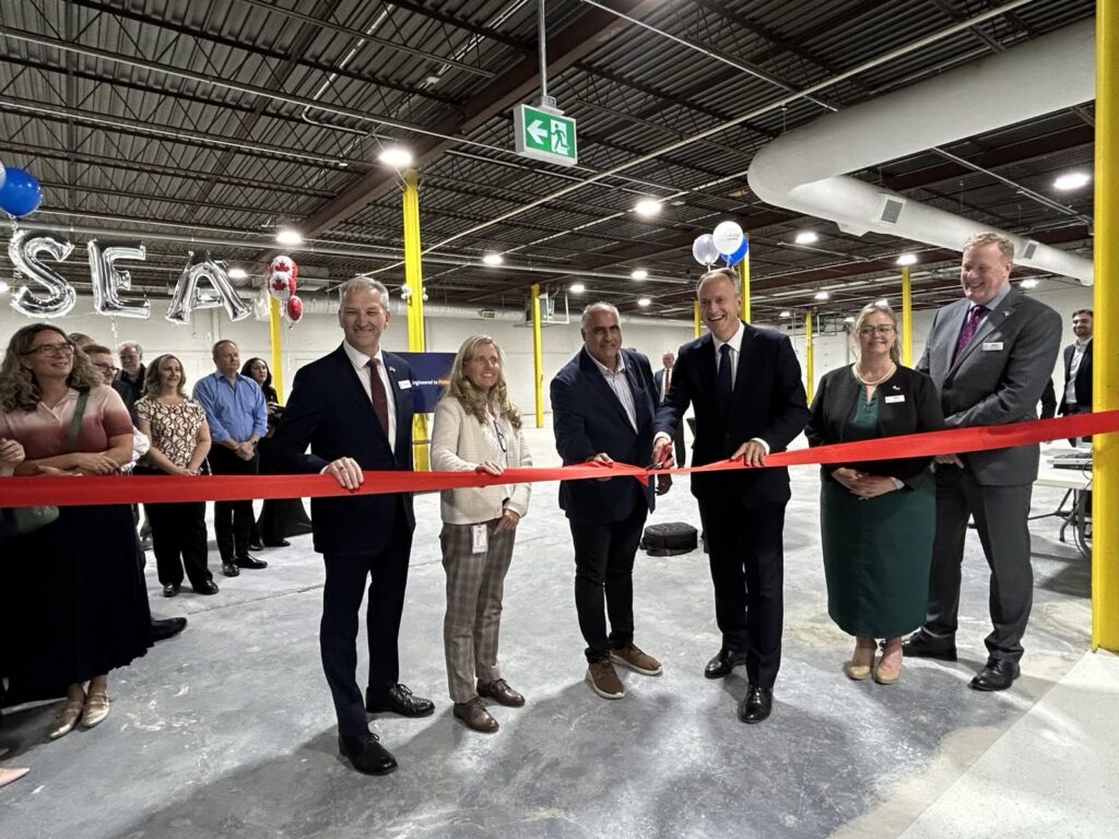 Business and government leaders cutting a ribbon at a facility opening, representing investment and growth in Ottawa.